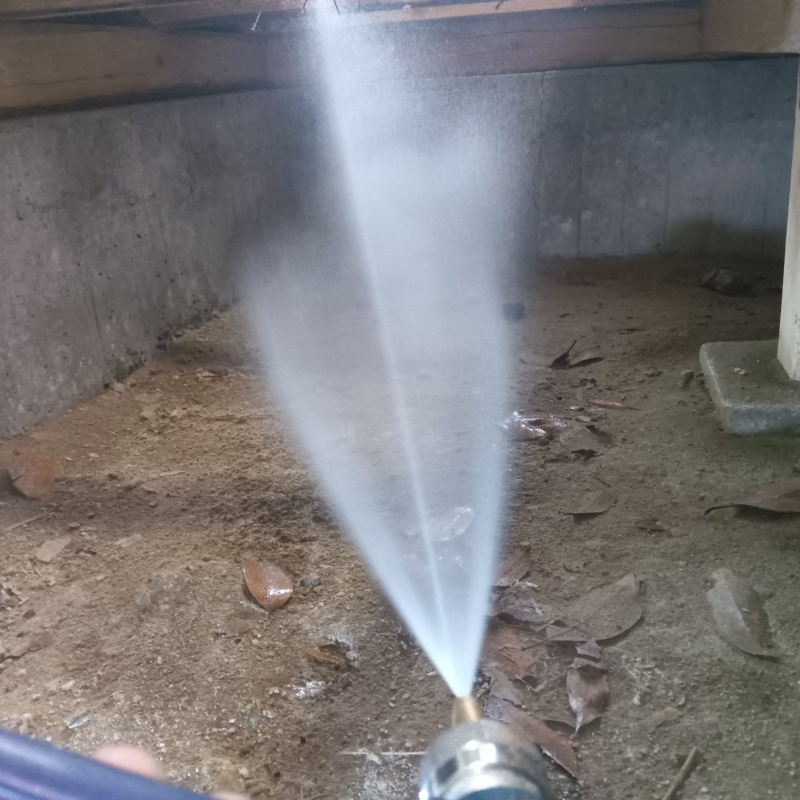 床下の土壌にシロアリ駆除剤を散布する様子