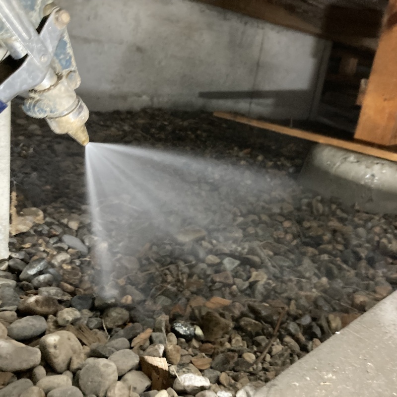 床下の土壌にシロアリ駆除剤を散布する様子