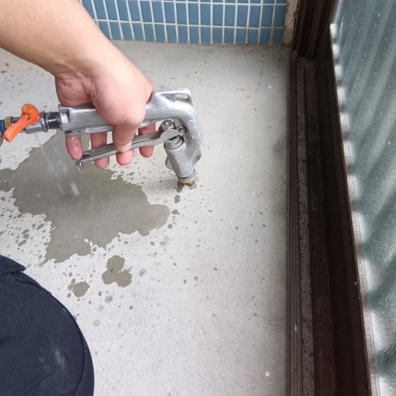 玄関の床にシロアリ駆除剤を注入する様子