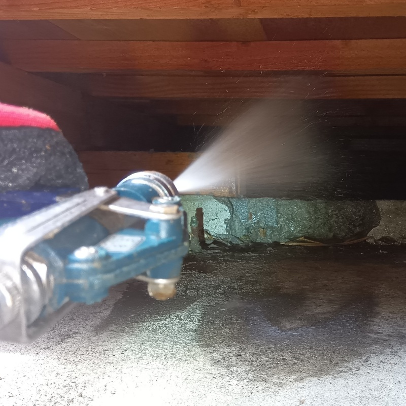 床下の木材にシロアリ駆除剤を散布する様子