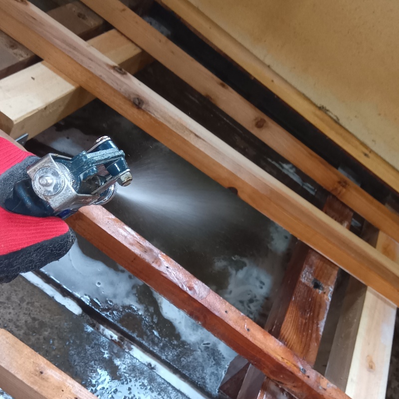 床下の土壌にシロアリ駆除剤を散布する様子