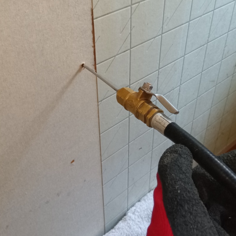 トイレの壁にシロアリ駆除剤を注入する様子