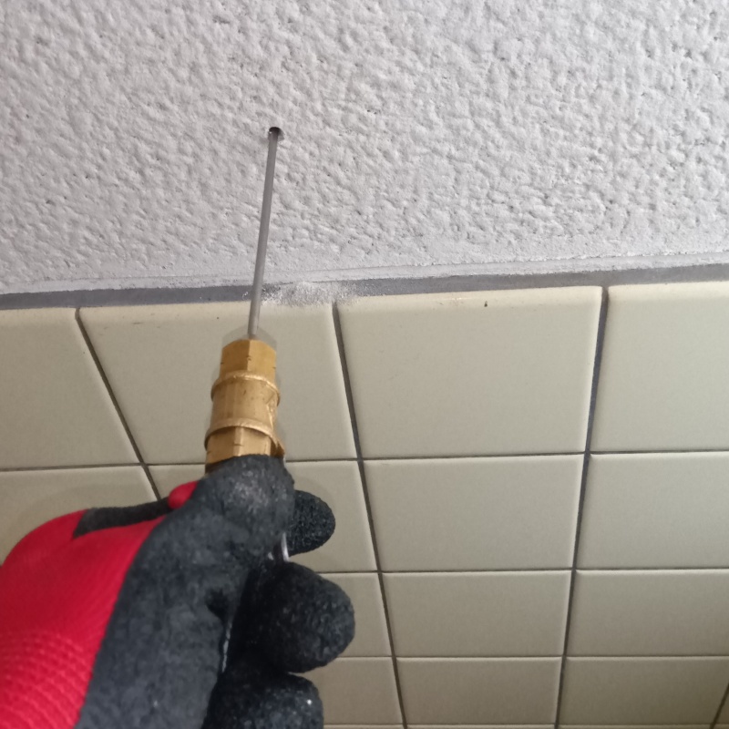 トイレの壁にシロアリ駆除剤を注入する様子