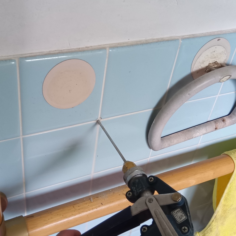 トイレの壁にシロアリ駆除剤を注入する様子