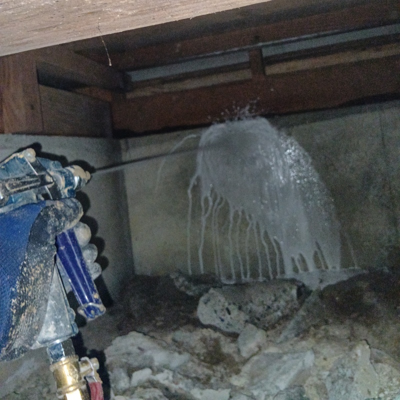 床下の基礎部分にシロアリ駆除剤を散布する様子