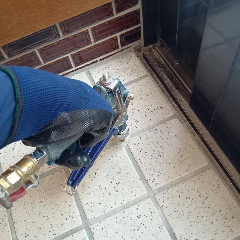 玄関の床にシロアリ駆除剤を注入する様子