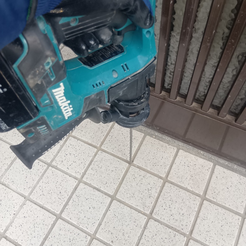 玄関の床にシロアリ駆除剤を注入する様子