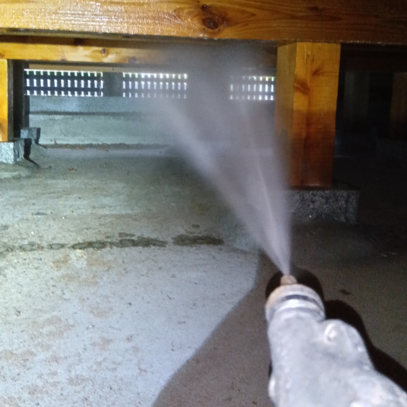 床下の基礎部分にシロアリ駆除剤を散布する様子
