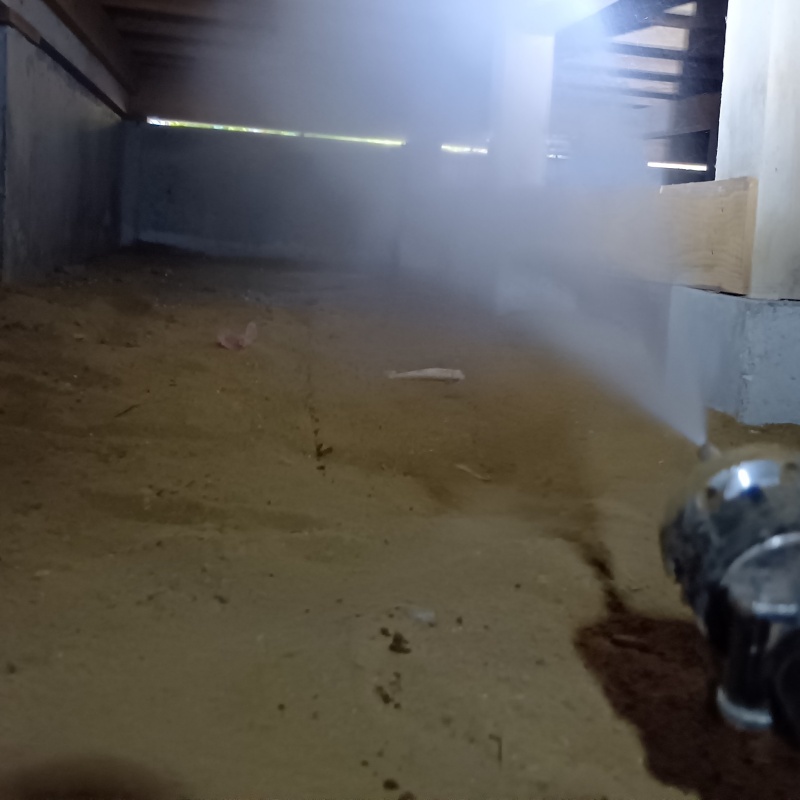 床下の土壌にシロアリ駆除剤を散布する様子