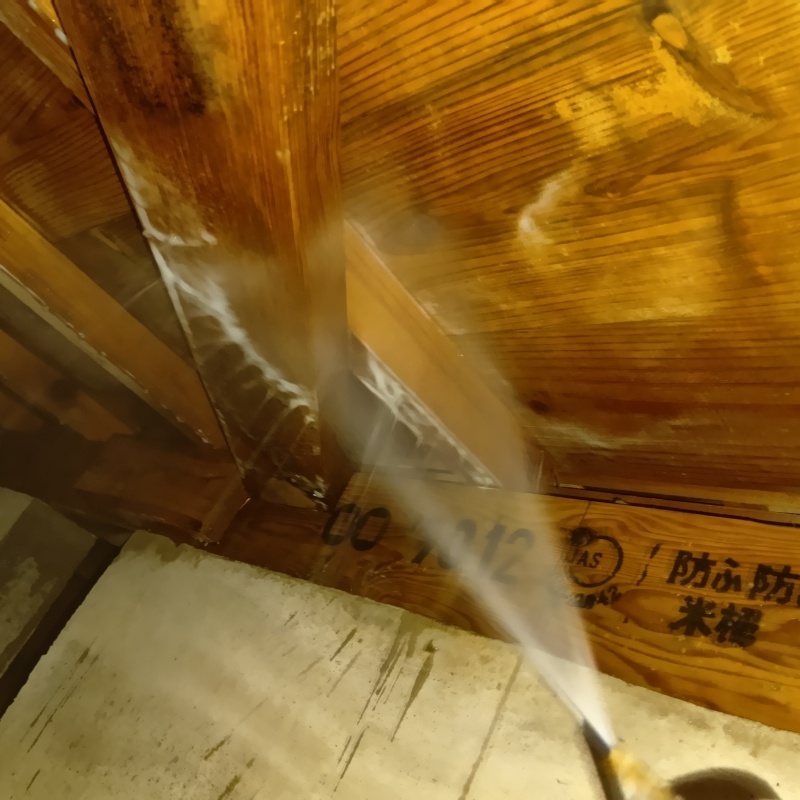 床下木材にシロアリ駆除剤を吹き付ける様子