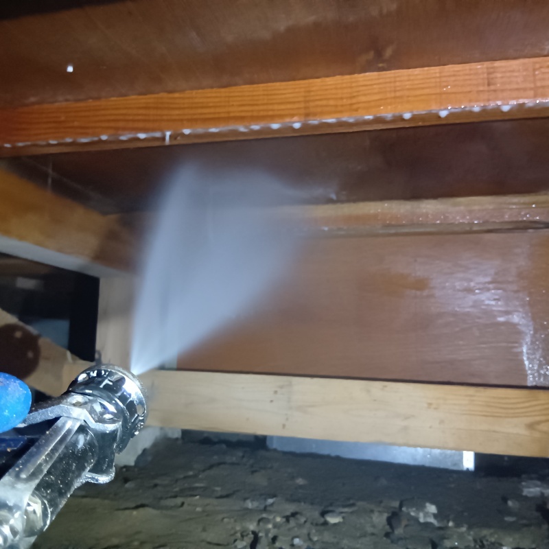 床下木材にシロアリ駆除剤を吹き付ける様子