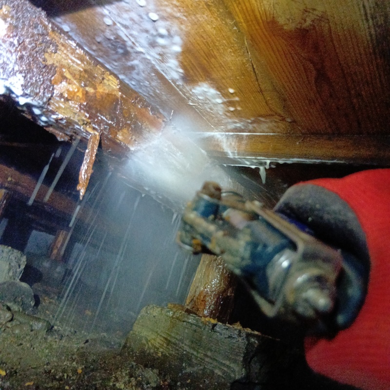 床下木材にシロアリ駆除剤を吹き付ける様子