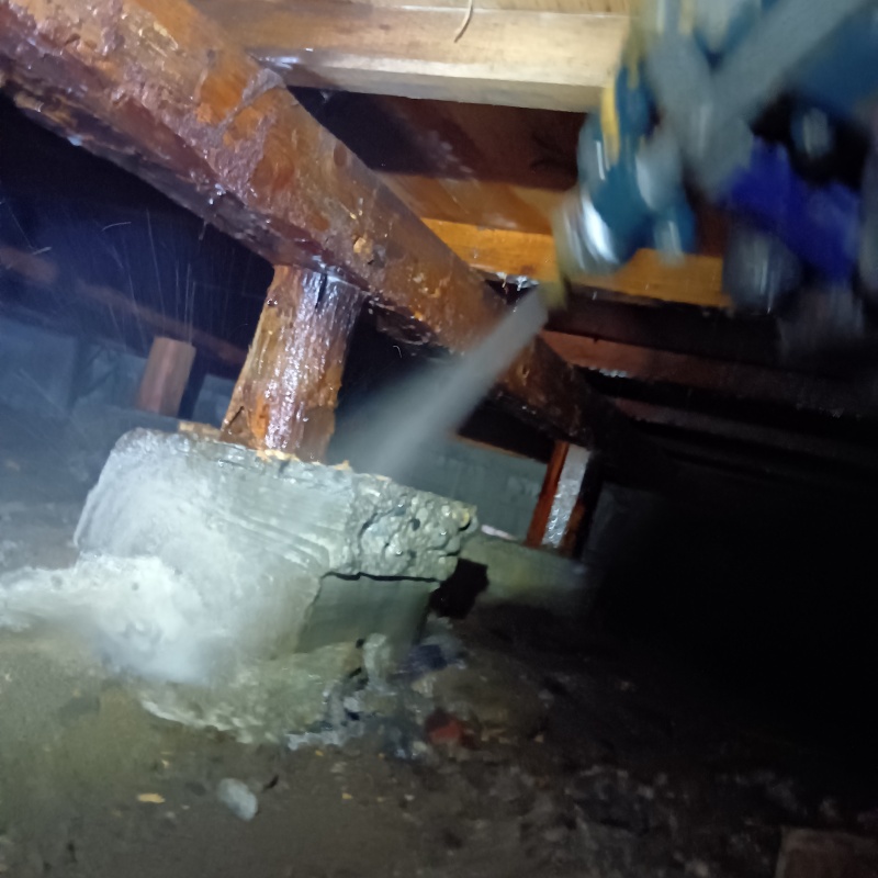 束石まわりにシロアリ駆除剤を吹き付ける様子