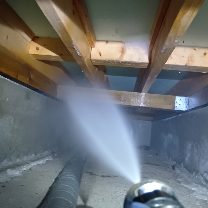 床下断熱材に防蟻剤を吹きつける様子