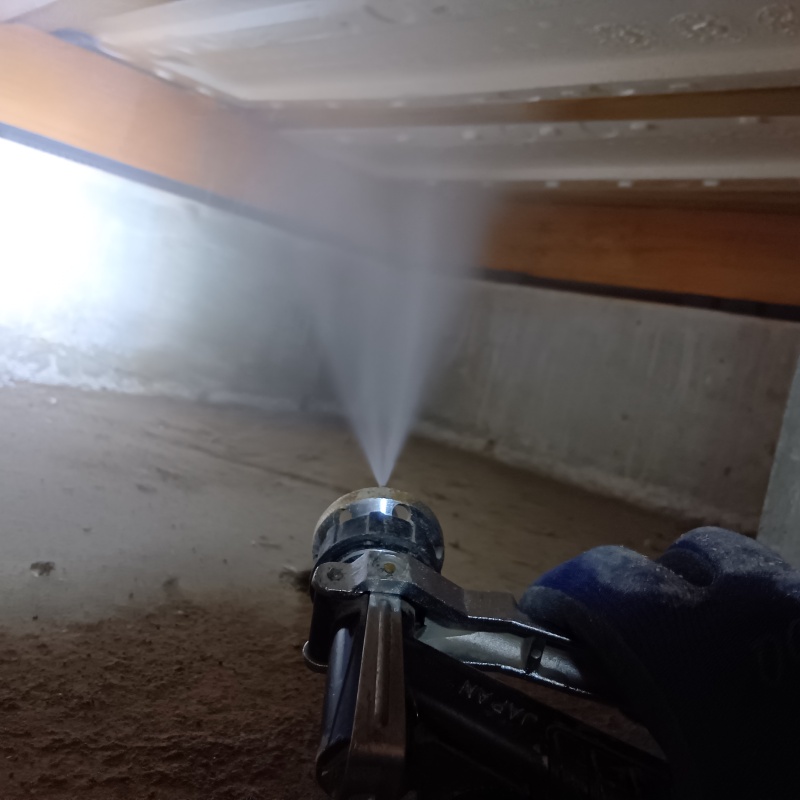 床下断熱材に防蟻剤を吹きつける様子