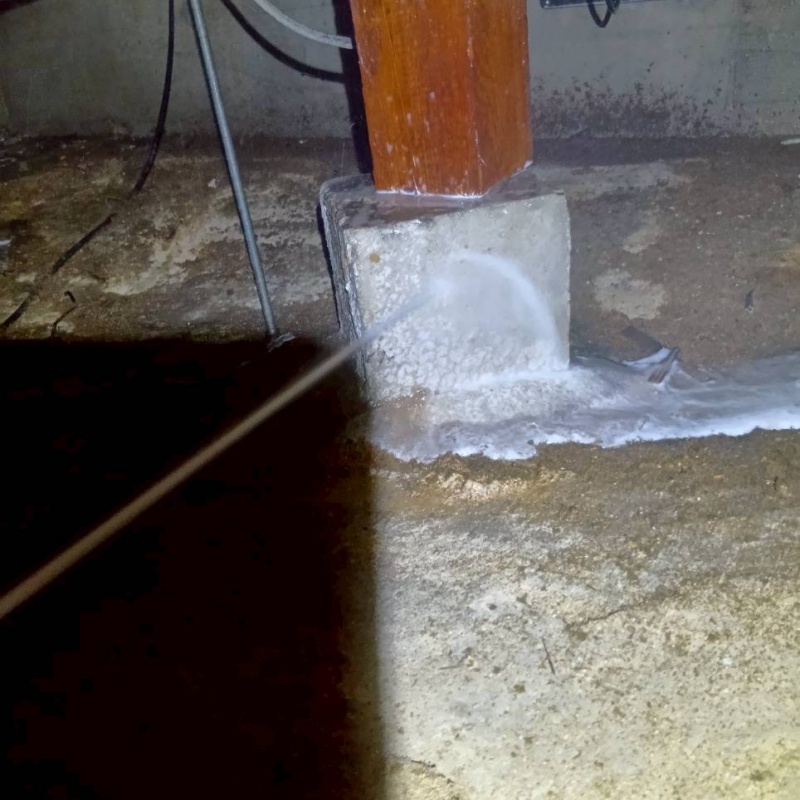 束石に防蟻剤を吹きつける様子