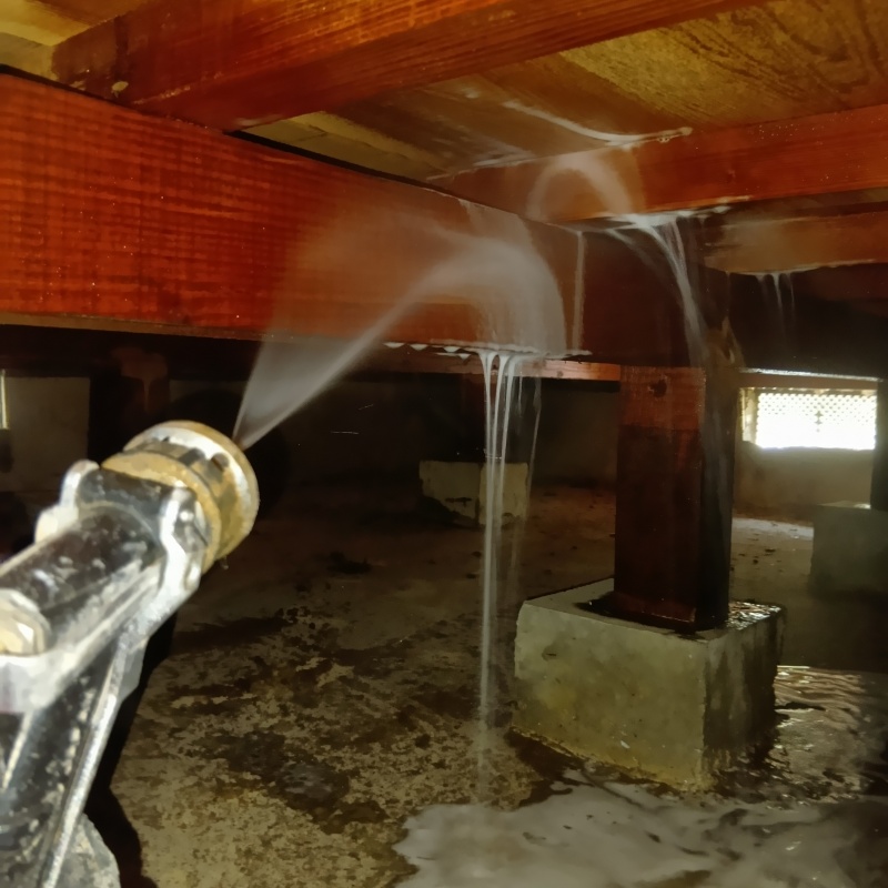 床下の木材にシロアリ駆除剤を吹きつけている様子