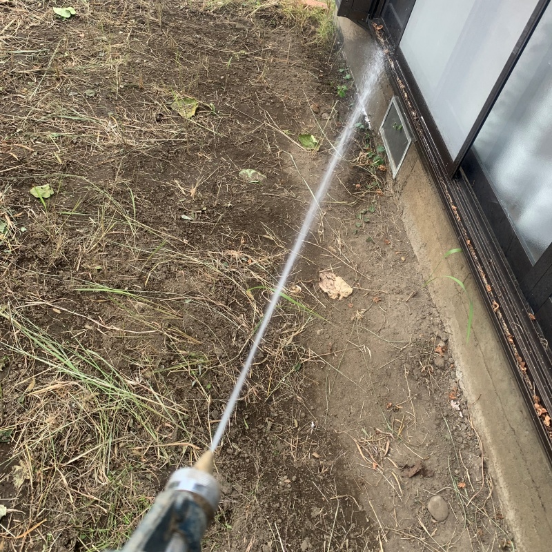 建物外周の土壌にシロアリ駆除剤を吹き付けている様子