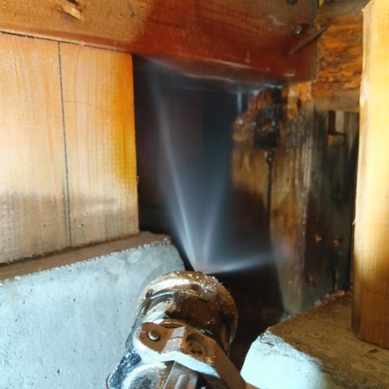 傷んだ木材にシロアリ駆除剤を吹きつけている様子