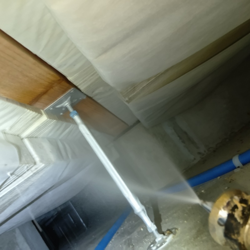 床下の木材にシロアリ駆除剤を吹きつけている様子