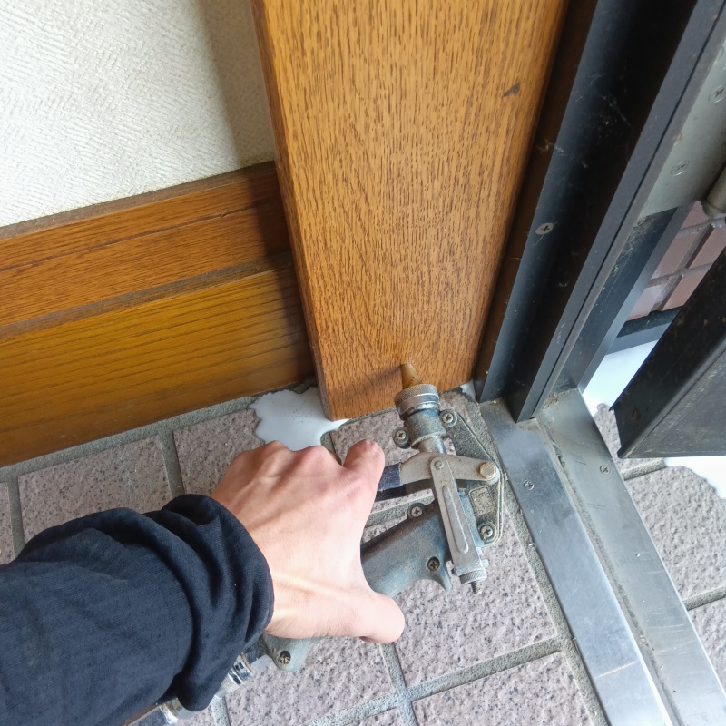 玄関付近の木材に穴を開けてシロアリ駆除剤を注入