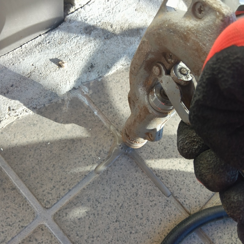 玄関先のタイルの目地からシロアリ駆除剤を注入