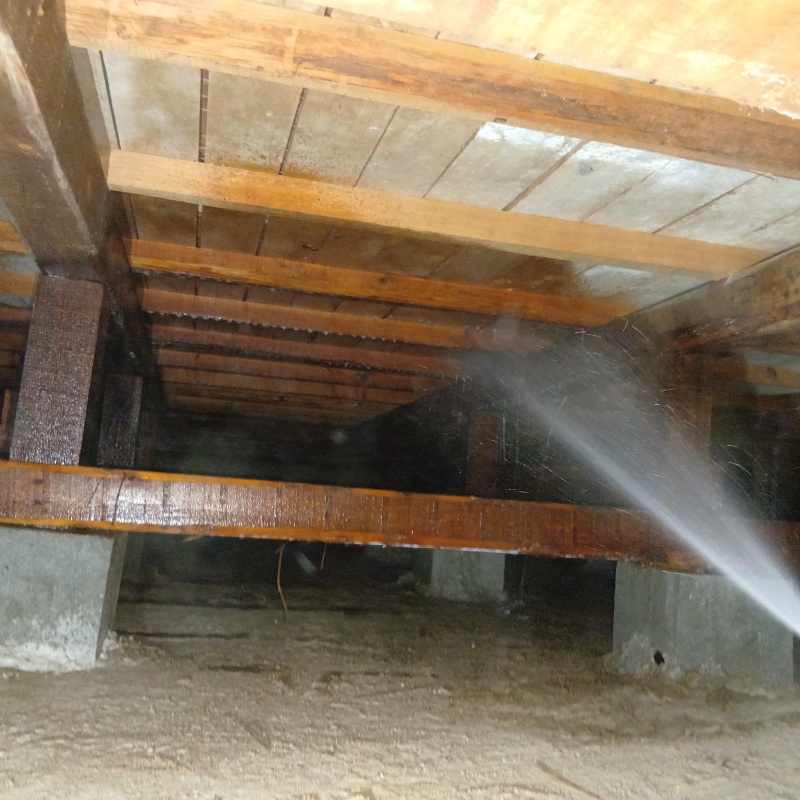 床下上部の木材にシロアリ駆除剤を散布する様子