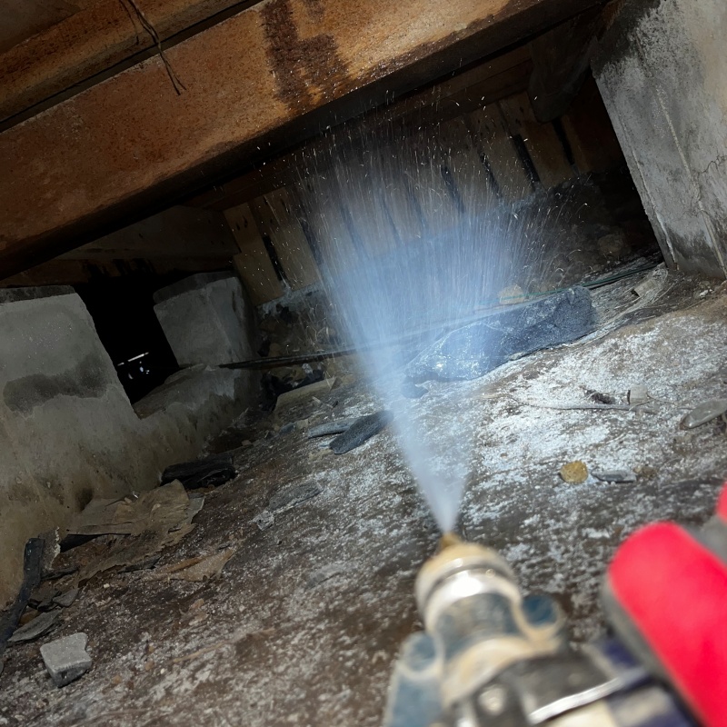 床下の土壌にシロアリ駆除剤を吹き付ける様子