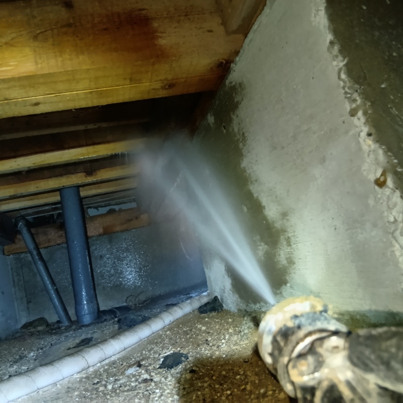束石まわりにシロアリ駆除剤を吹き付ける様子