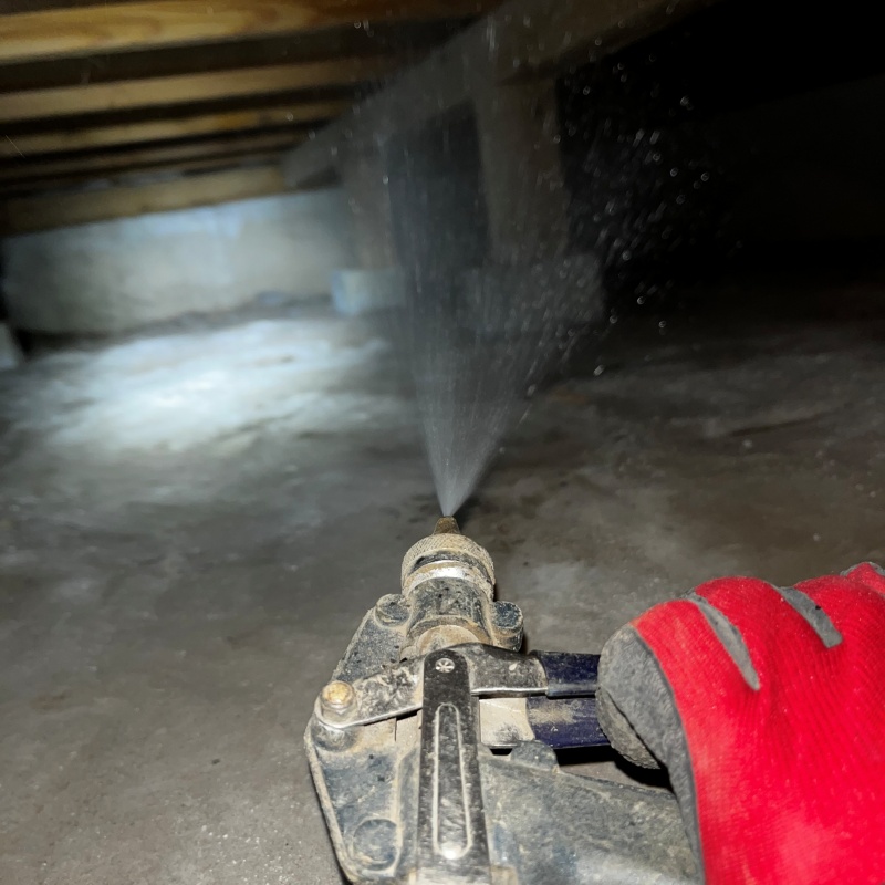 束石まわりにシロアリ駆除剤を吹きつけている様子