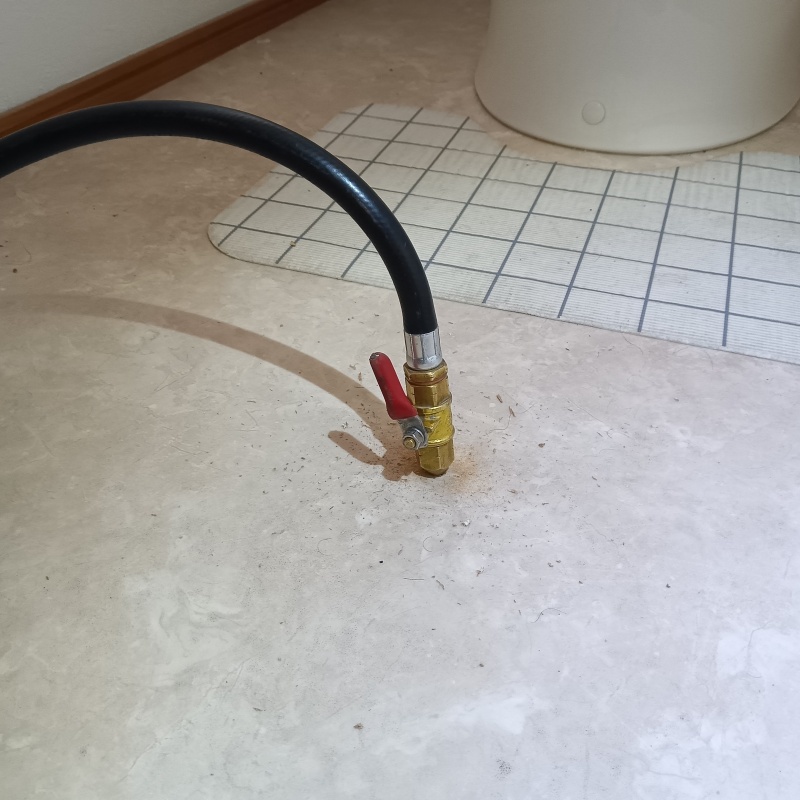 トイレの床にシロアリ駆除剤を注入する様子