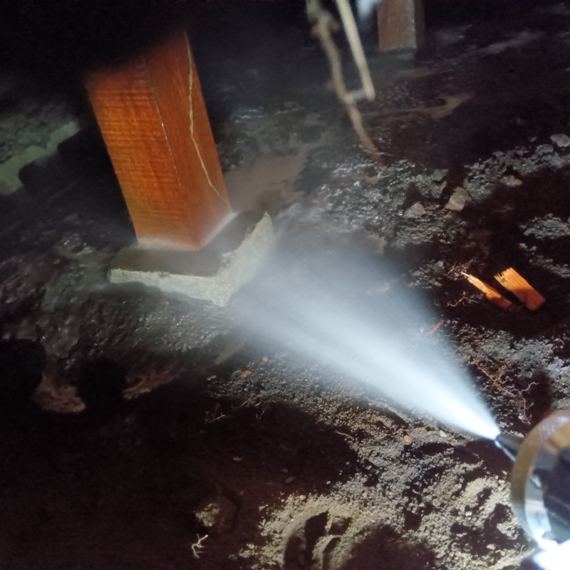 床下の土壌にシロアリ駆除剤を散布する様子