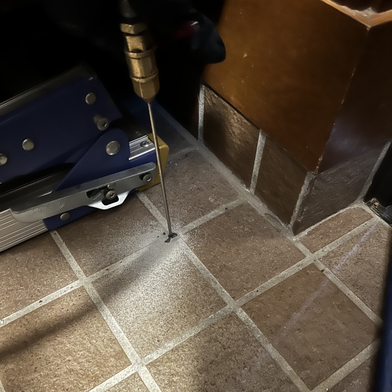 玄関の床にシロアリ駆除剤を注入する様子