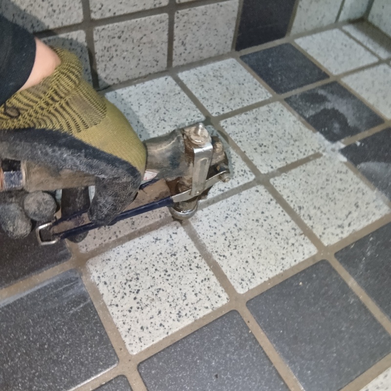 玄関の床にシロアリ駆除剤を注入する様子