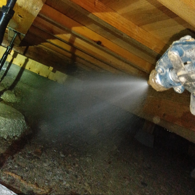 床下の土壌にシロアリ駆除剤を散布する様子
