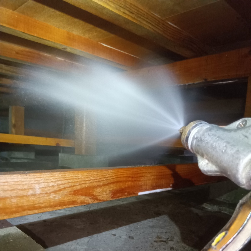 床下の木材にシロアリ駆除剤を散布する様子
