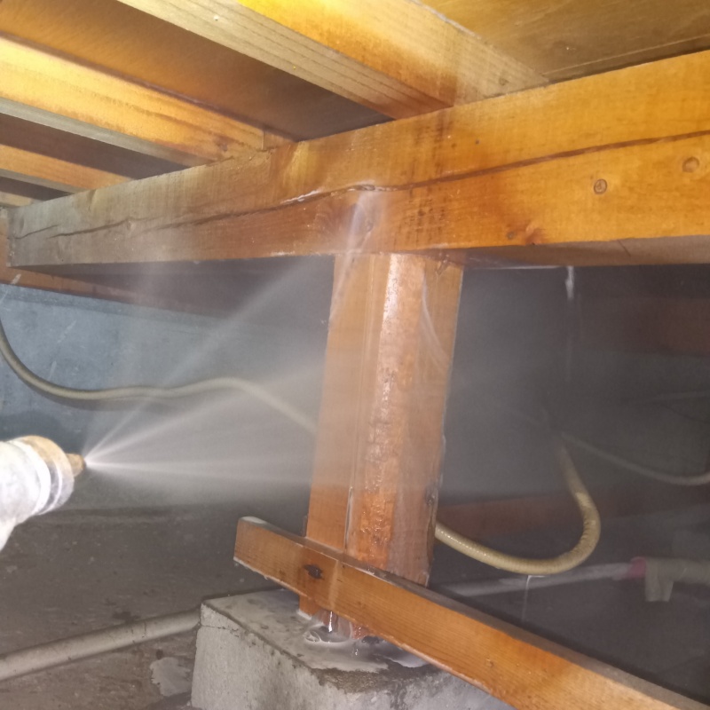 床下の木材にシロアリ駆除剤を散布する様子