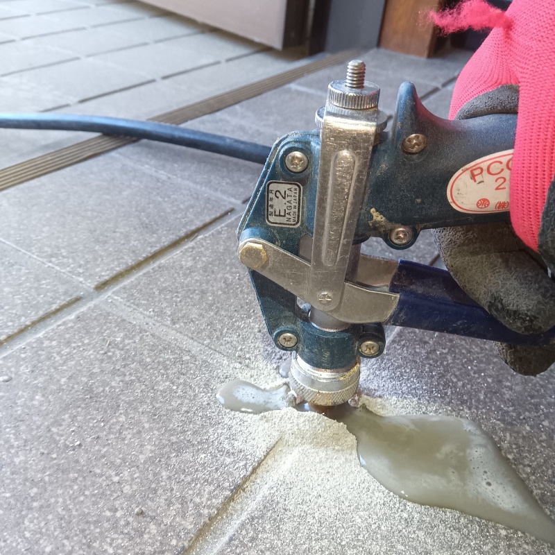 玄関の床にシロアリ駆除剤を注入する様子