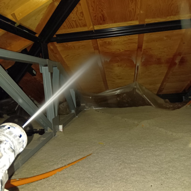 屋根裏の木材にシロアリ駆除剤を散布する様子