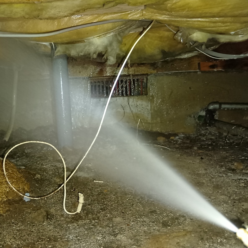 床下の土壌にシロアリ駆除剤を散布する様子