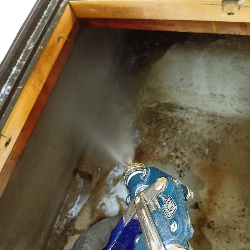 床下の土壌にシロアリ駆除剤を散布する様子