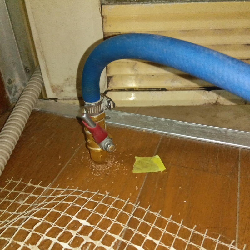脱衣室の床にシロアリ駆除剤を注入する様子