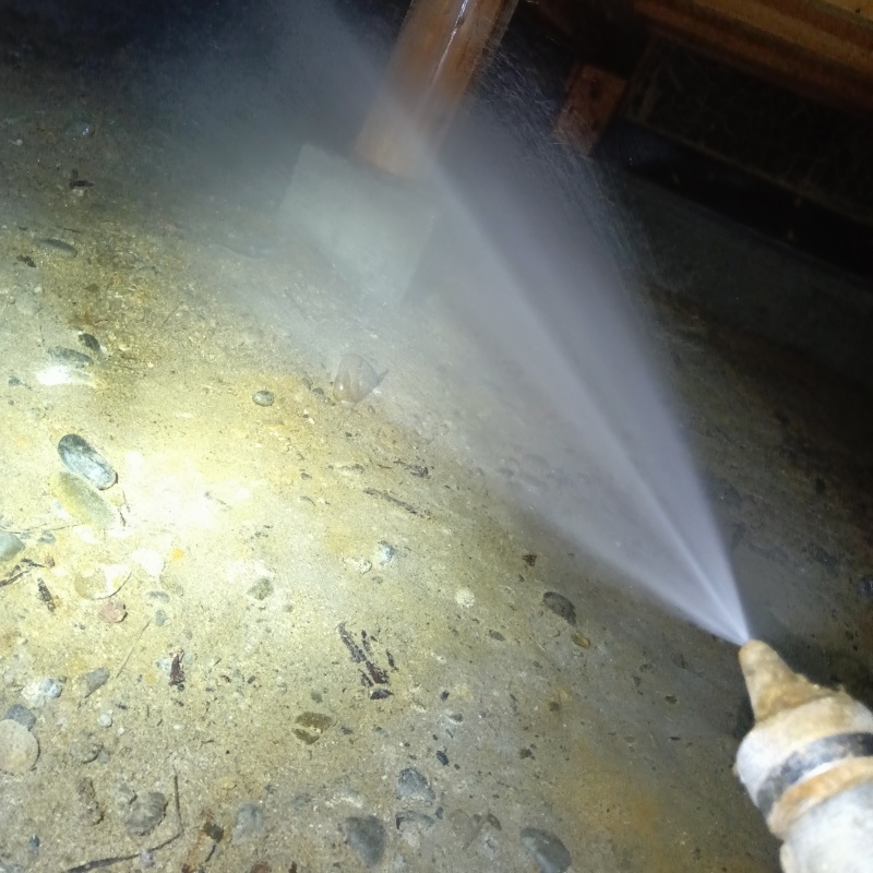 床下の土壌にシロアリ駆除剤を散布する様子