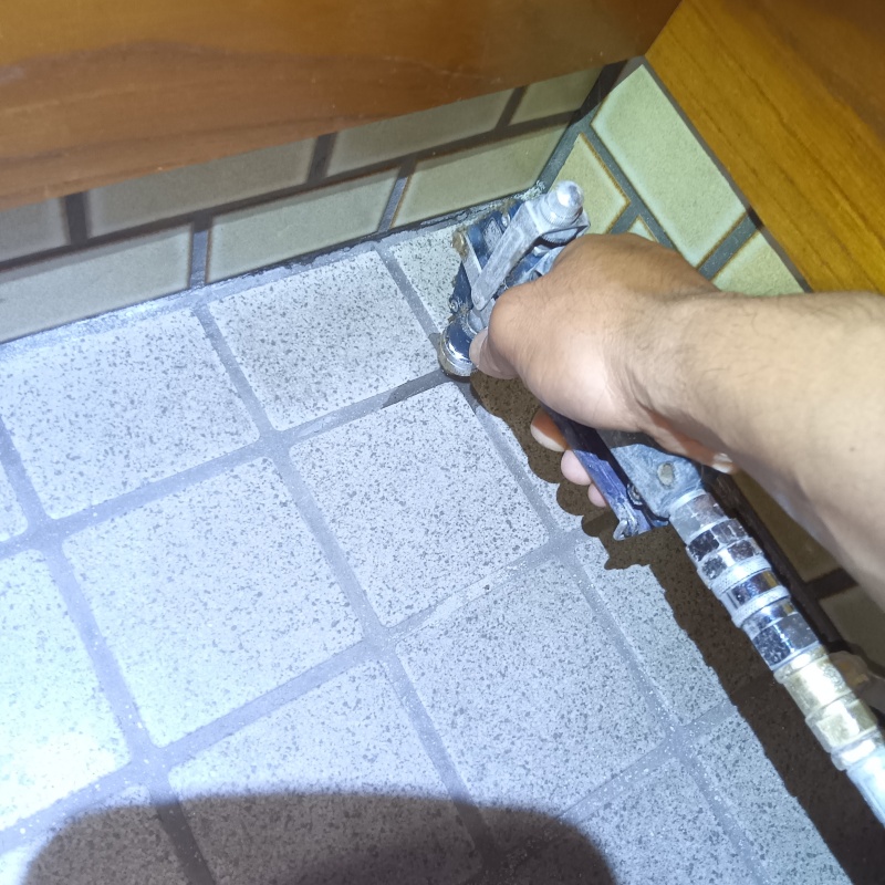 玄関の床にシロアリ駆除剤を注入する様子