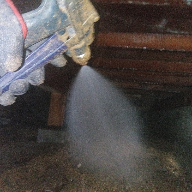 床下の土壌にシロアリ駆除剤を散布する様子