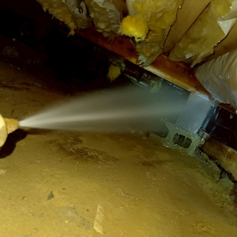 床下の土壌にシロアリ駆除剤を散布する様子