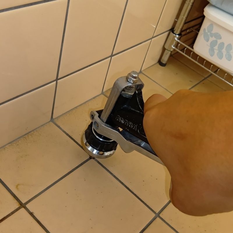 トイレの床にシロアリ駆除剤を注入する様子