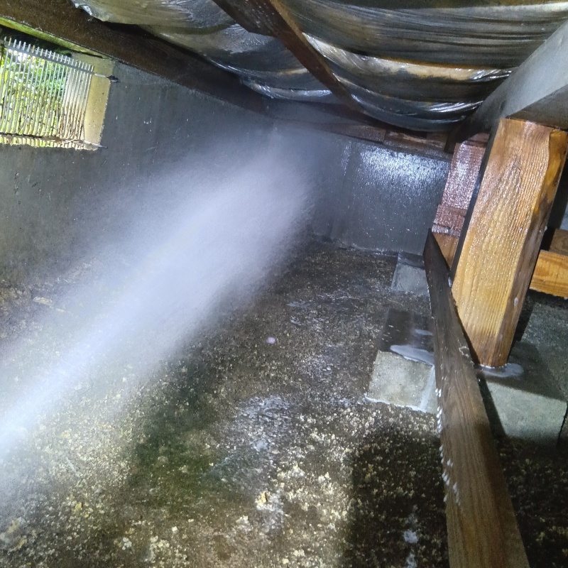 床下の土壌にシロアリ駆除剤を散布する様子