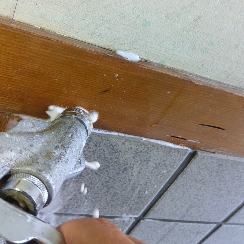 玄関の壁にシロアリ駆除剤を注入する様子
