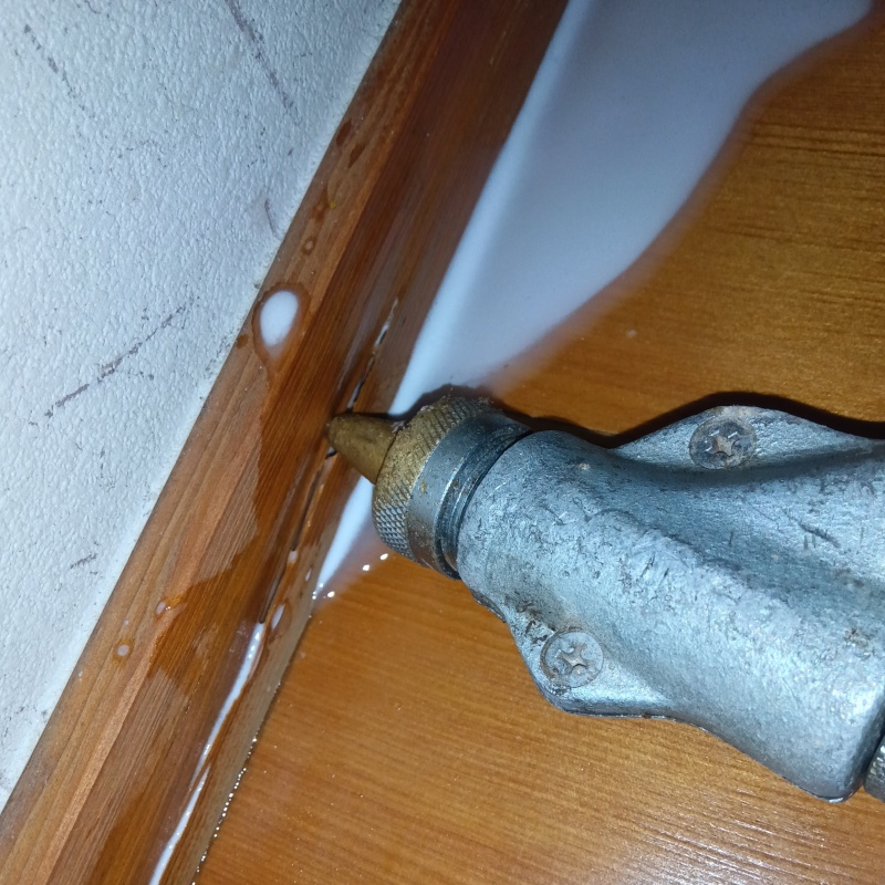 室内の巾木にシロアリ駆除剤を注入する様子